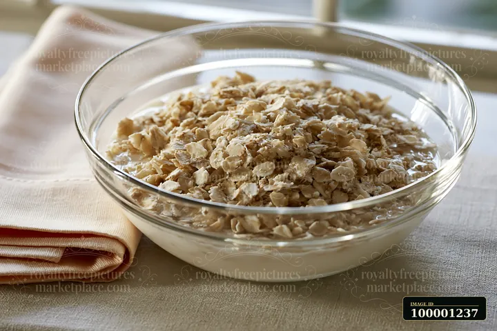This bowl holds a cream dose with oat flakes, placed on a table next to a cloth napkin.