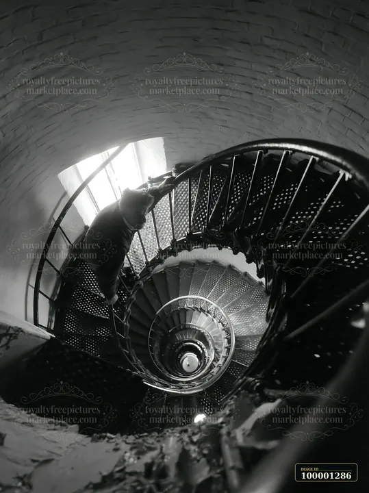 A lighthouse maintenance worker climbs a spiral staircase inside the lighthouse, focusing on the task.