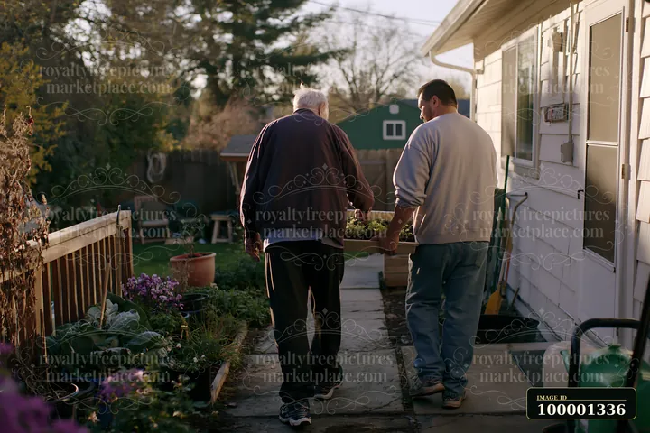 A person with Parkinson's disease receiving support walks with a caregiver in a garden.