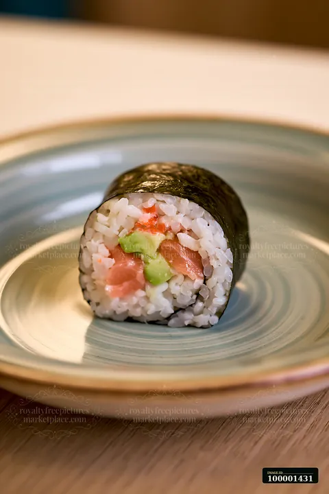 A single sushi roll on ceramic plate features rice, fish, and avocado.