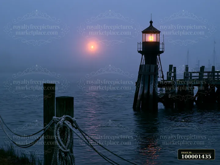 A lighthouse stands in heavy ocean fog, casting its light over the water.
