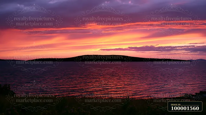 A vibrant sunset casts colorful hues over an island.