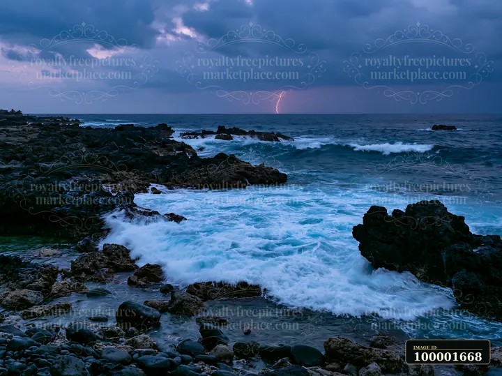 Waves crash on rocky coastline as a bolt of lightning strikes over the ocean.