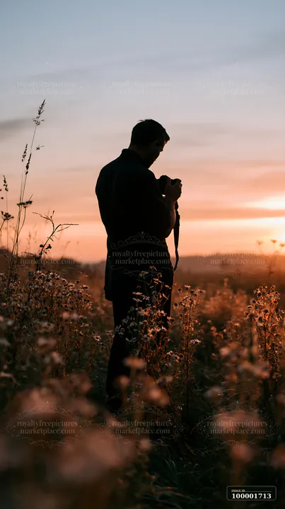 A man photographs meadow flowers at sunset, capturing the warm colors and soft light.