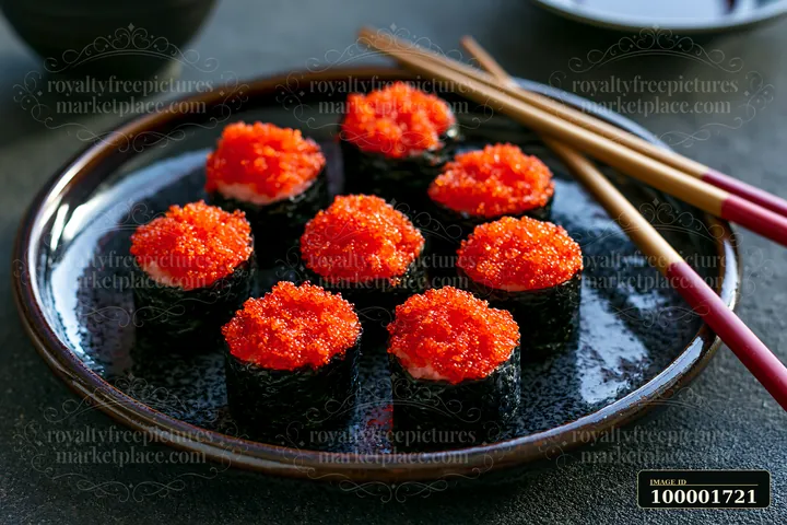A tobiiko roe sushi platter features rolls topped with vibrant red caviar served on a dark plate.