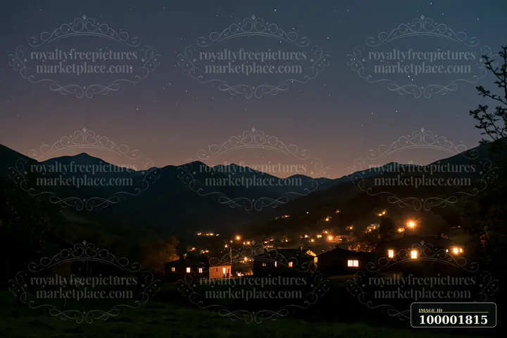 Stars fill the night sky above a mountain valley where houses glow with warm light.