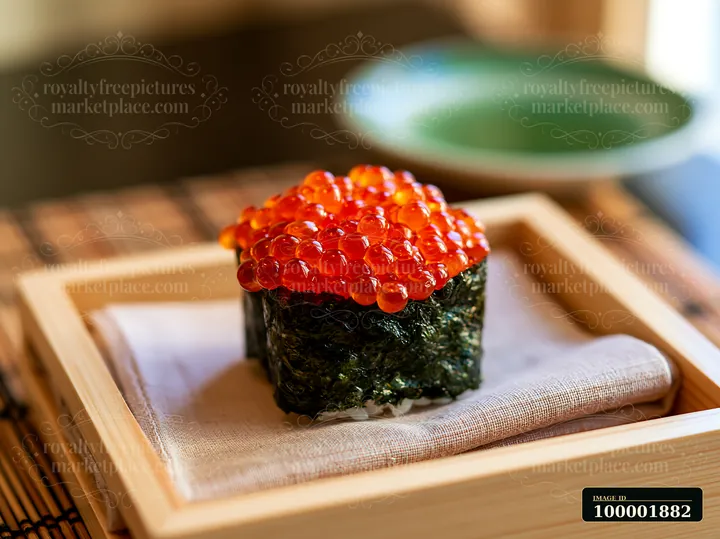 Bright orange ikura salmon roe sushi sits on a bamboo tray with a cloth.