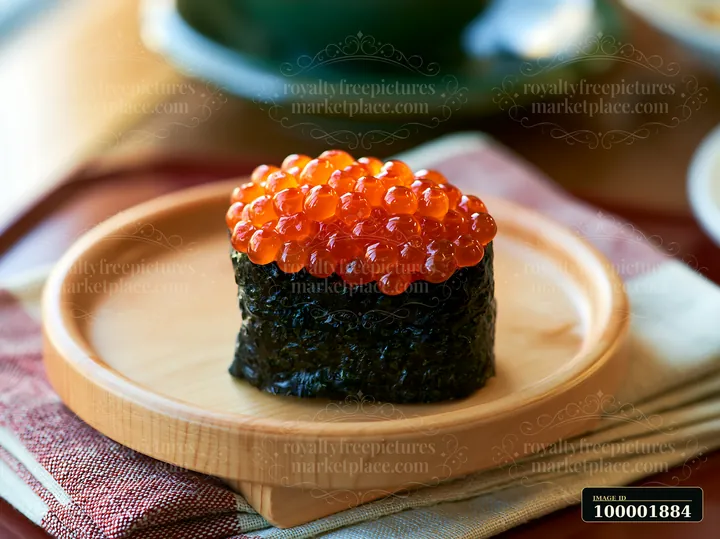 This close up shows ikura salmon roe sushi placed on a wooden plate, highlighting the vibrant orange roe on top of a piece of sushi.