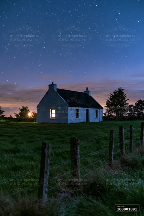 A house in a meadow beneath stars stands in the dark with light shining from a window.