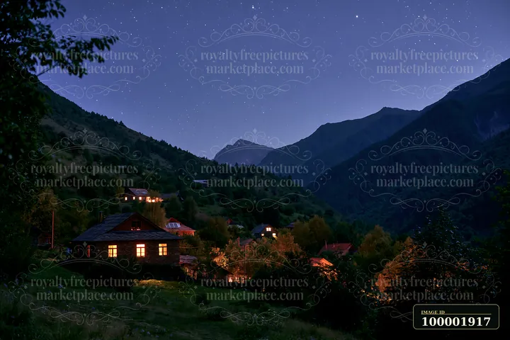 A starry night above a tranquil mountain valley shows homes lit softly along the hillside.