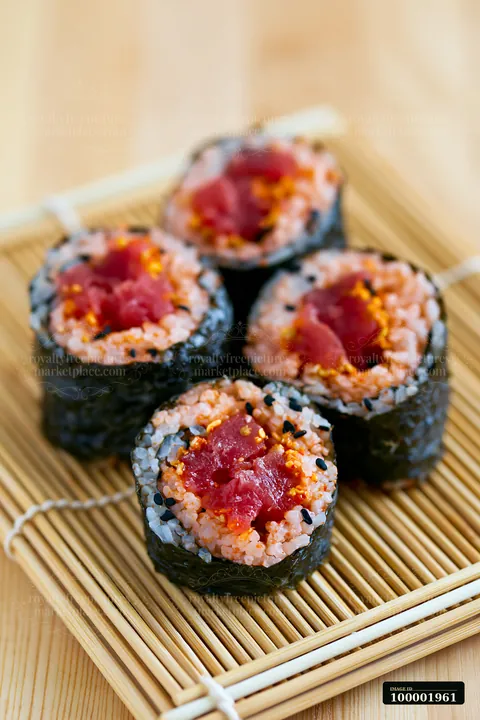 A close view of a spicy tuna roll placed on a bamboo mat.