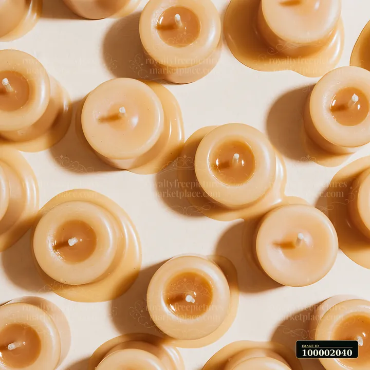 Vanilla candles on neutral background showcase a collection of small, round candles arranged closely.