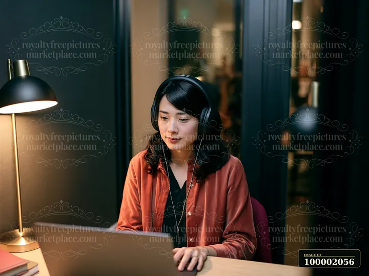 A woman works at a laptop in a contemporary office setting.