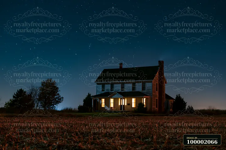 A country house stands under a starry sky with lights shining from its windows.