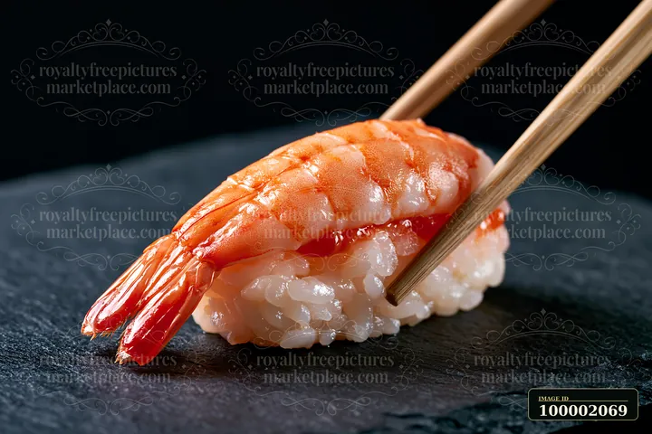 A single sushi piece with chopsticks is placed on a dark slate surface.