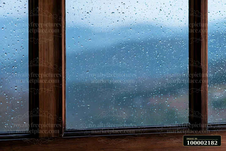 Raindrops on timber window create a backdrop of blurred hills.