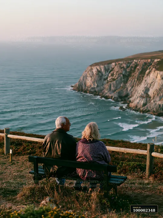 A couple sits on a bench enjoying the view of the coastline with sustainable tourism sign.