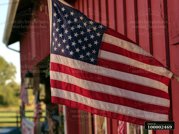 An American flag waving in gentle breeze hangs next to a red barn.