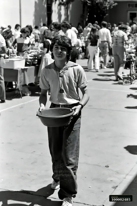A young person carries a bowl while walking through a bustling community potluck buffet.