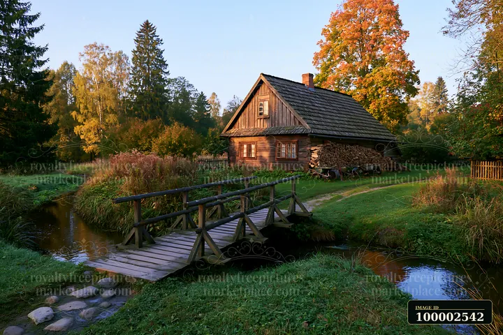 A rural cottage with firewood stack stands beside a stream, connected by a wooden bridge.