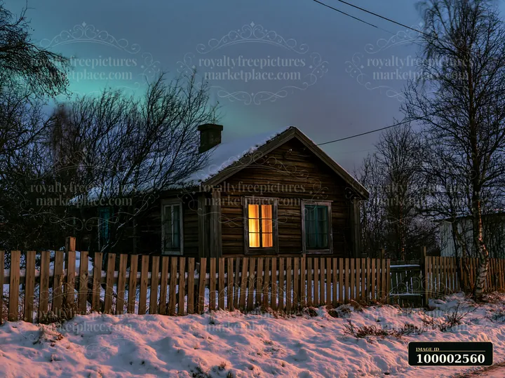 A wooden cottage sits surrounded by snow and trees under the northern lights.