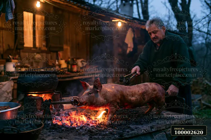 A cook turns a whole suckling pig roasting on a spit over a charcoal grill in front of a rustic wooden kitchen setting during twilight.