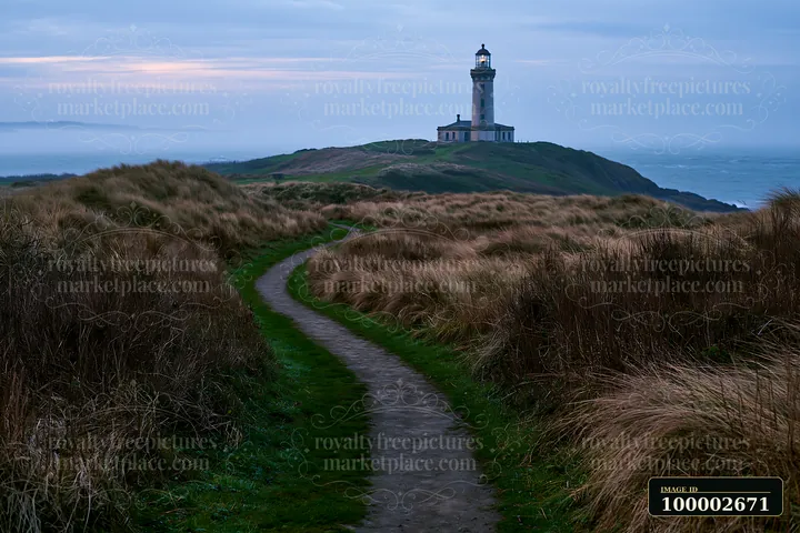 A lighthouse stands tall on a cliff, surrounded by coastal dunes and grass.