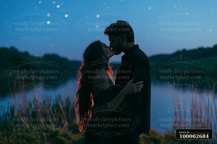 A happy couple kissing beneath stars in nature at lakeside during twilight.