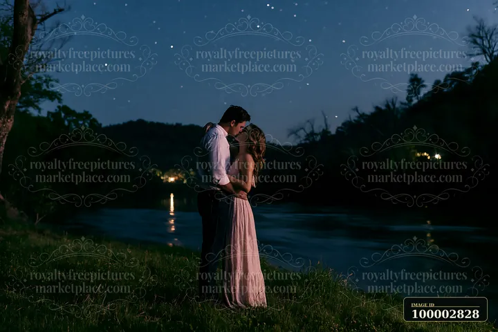 A happy couple kissing beneath stars in nature stands by a riverbank.