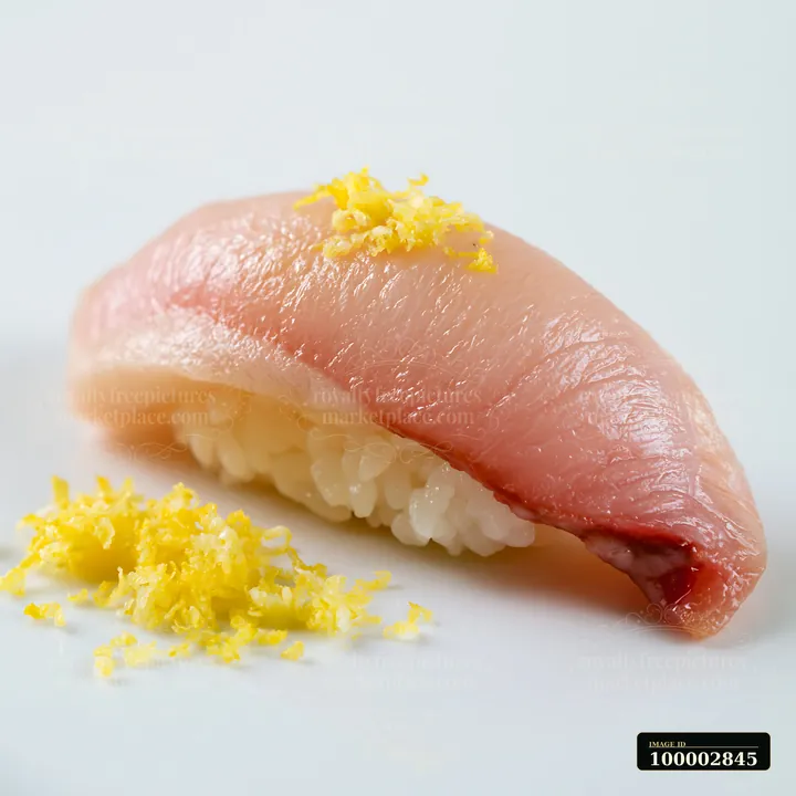 Sushi with lemon garnish close-up shows a piece of sushi topped with yellow lemon zest on a plain white plate.