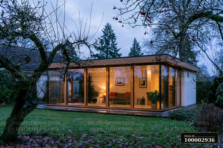 A garden house features glowing glass walls and simple furniture.