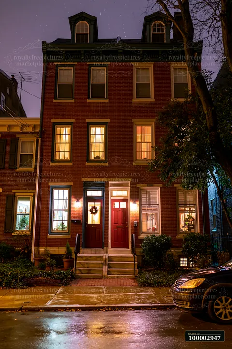 A charming house displays lit windows under a meteor shower on a clear night.