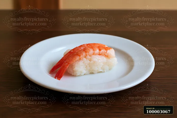 One shrimp sushi piece on white plate sits on a wooden table.
