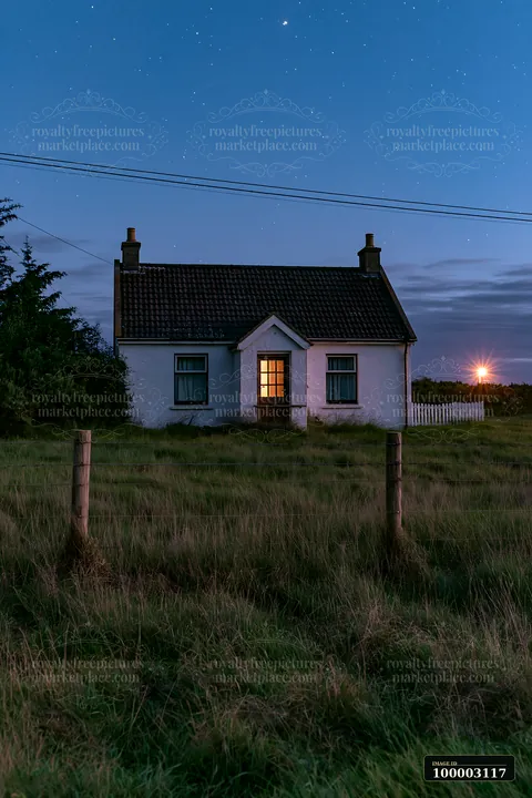 A small house stands alone in a meadow at night.