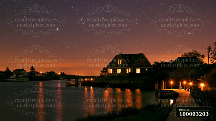 A coastal home sits by the water with a clear view of the ocean horizon under a starry sky.