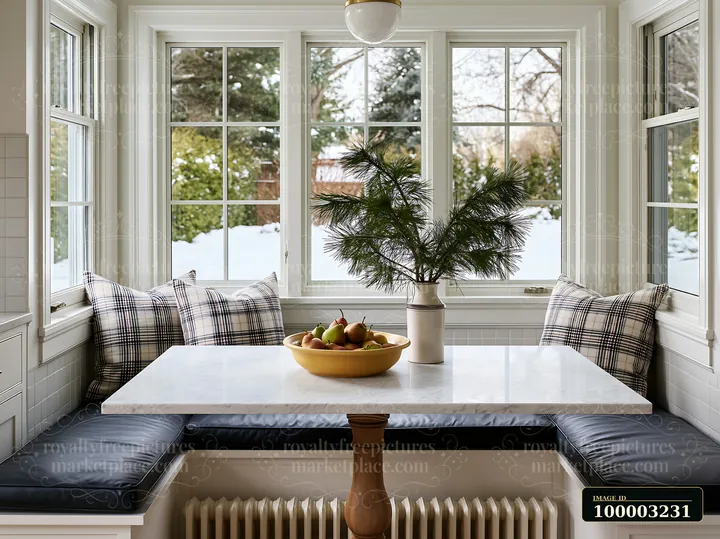 A cozy kitchen features a marble dining table with a bowl of fruits and a pine branch centerpiece.