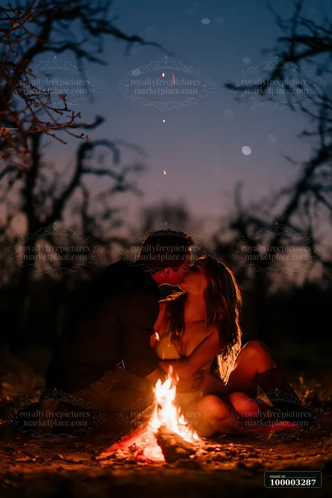 A couple kissing beside a campfire under stars in a dark outdoor setting.