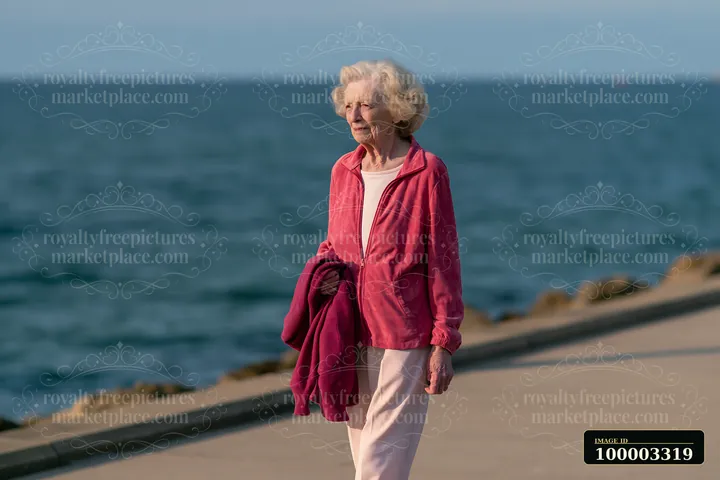 Elderly woman with Parkinson's disease walking outdoors near the coast.