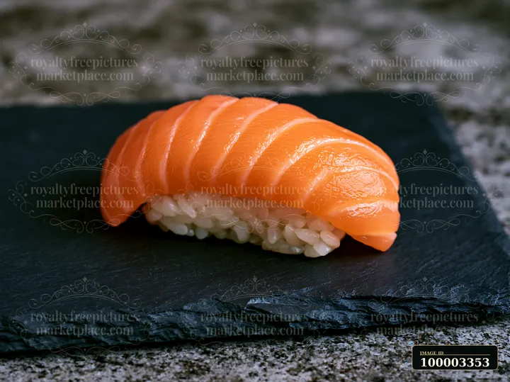 One salmon nigiri on slate plate shows a piece of sushi with slices of salmon on rice.