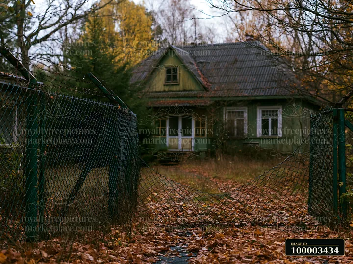 The photograph shows a Soviet abandoned building situated behind a broken fence.