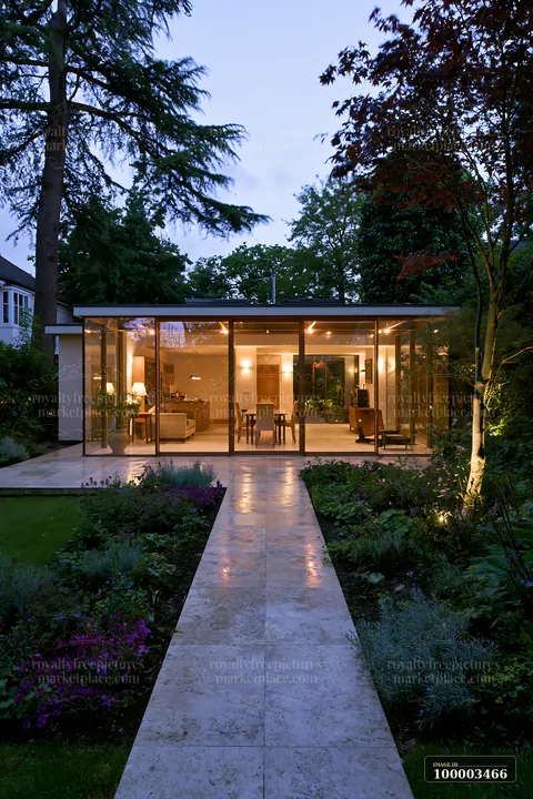 A modern empty garden house with glowing glass walls stands in a peaceful setting.