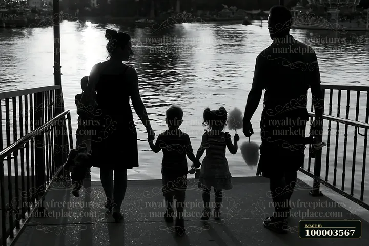 A family is leaving the kirmes with prizes, holding hands and walking by the water.