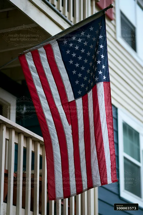 An American flag is displayed on a balcony of an apartment building.