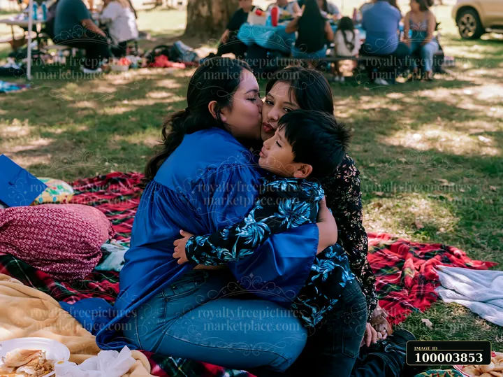 A group of friends and family gather in a park to celebrate graduation.