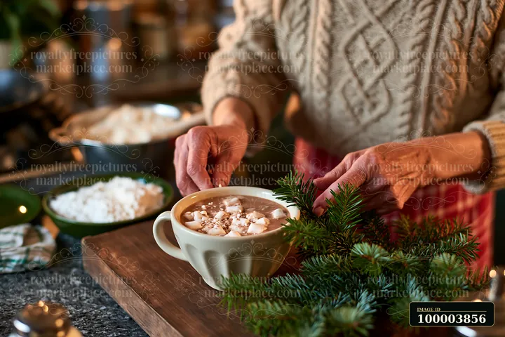 Warm cocoa with marshmallows is set on a kitchen counter.
