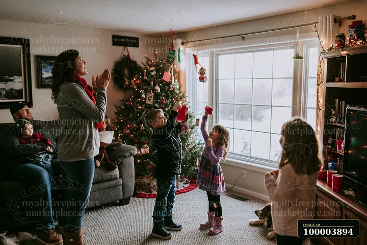 A family enjoys a holiday celebration in a cozy living room, filled with decorations.