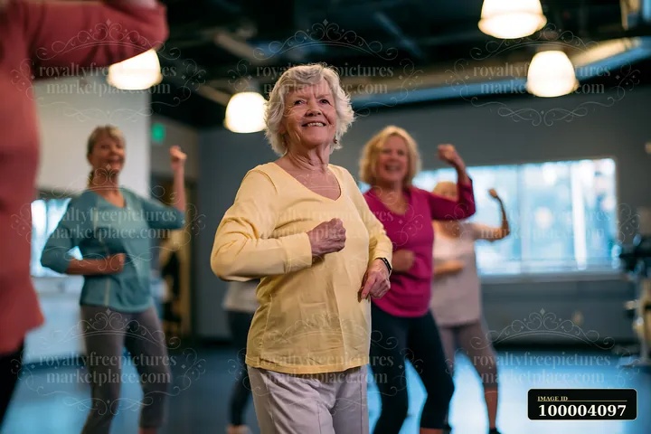 Senior women participate in a dance fitness class in a brightly lit studio.