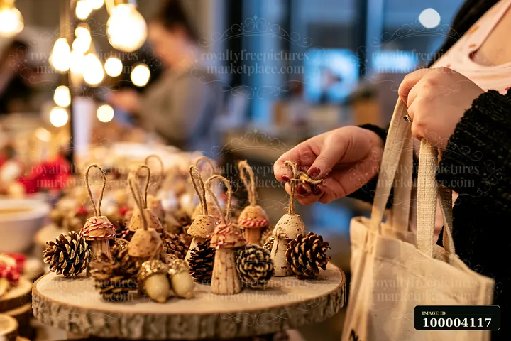 A shopper examines handmade ornaments at a Christmas market stall.