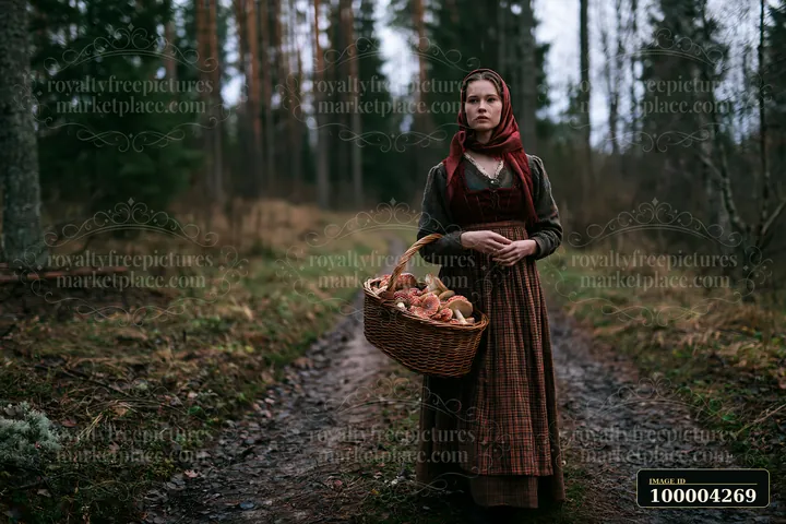 Woman in traditional dress holds a basket of mushrooms on a wooded forest path.