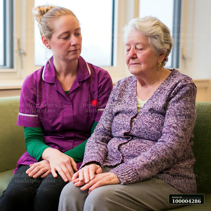 A caregiver provides comfort to an elderly patient in a healthcare setting.